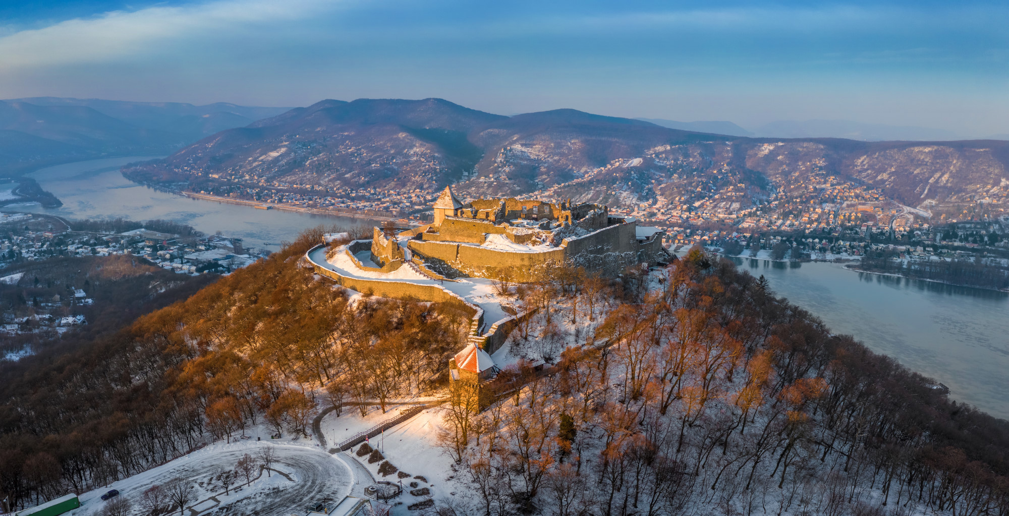 Visegrad, Hungary - Aerial panoramic view of the beautiful snowy high castle of Visegrad at sunrise on a winter morning with Dunakanyar at background